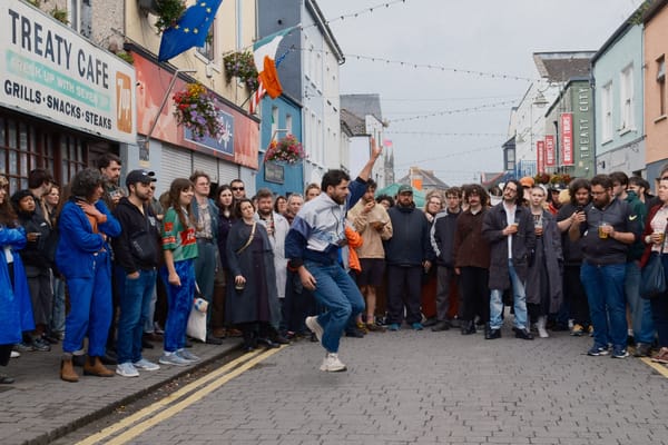 A dancer strikes an arresting pose, surrounded by a circular crowd of people, on King's Island, Limerick.